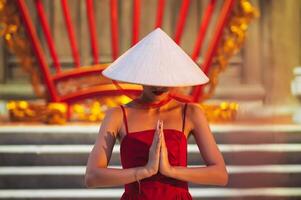 woman in traditional Vietnamese Non La hat prays at a temple on a Buddhist pagoda in Vietnam. The concept of travel in Asia photo