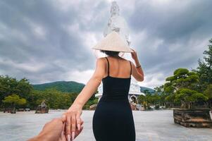 back of girl tourist traveler at Lady Buddha statue at Linh Ung Pagoda in Da Nang in Vietnam. Follow me concept of travel and tourism in Asia photo