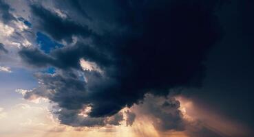 dark dramatic clouds in cloudy sky in a storm and rain at sunset photo