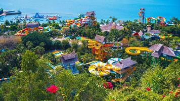 big water park with slides and a swimming pool at the resort in summer. Amusement park with aquapark by sea on VinPearl Island in Nha Trang in Vietnam aerial top view photo