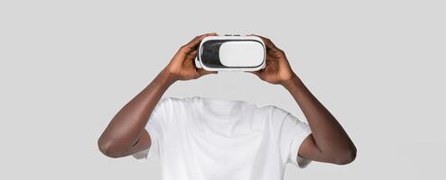 A person engages with virtual reality technology using a headset that covers their eyes, creating an illusion of a headless figure. The background is simple and neutral. photo