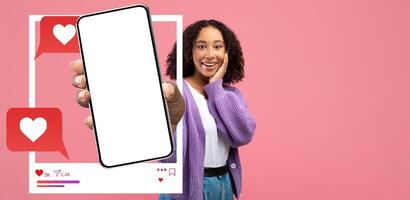 A joyful influencer holds up a smartphone displaying a blank screen, emphasizing the importance of social media interaction. This colorful collage features heart icons around her. photo