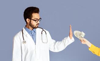 Reducing bribery and corruption. Honest Indian doctor refusing to take money from patient on violet background, panorama photo