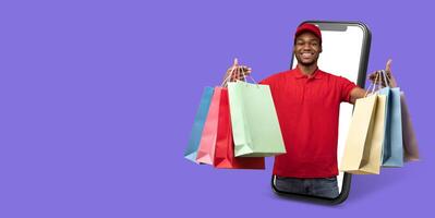 A cheerful delivery man holds several shopping bags while interacting with a smartphone. This showcases the convenience of online shopping on a large screen, emphasizing modern commerce. photo