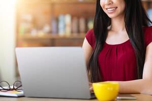Job Search Websites. Young Asian Woman Using Laptop In Cafe, Checking Vacancies In Internet, Uploading Her Cv, Typing On Computer Keyboard, Working Online, Sitting At Table In Cafeteria, Copy Space photo