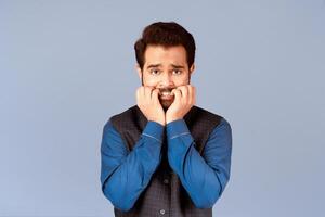 Terrified Indian guy biting his nails in panic over lilac background photo