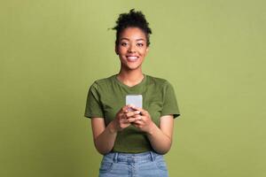 Cool Application. Smiling african lady using smart phone on green studio background and looking at camera photo