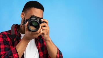 Photography. Professional Photographer Man Holding Modern Camera Taking Photo Standing In Studio Over Blue Background.