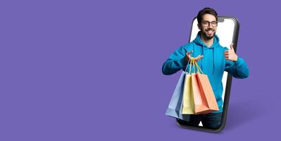 A smiling buyer holds shopping bags while interacting with a smartphone. The vibrant background emphasizes online shopping and digital commerce in a modern setting. photo