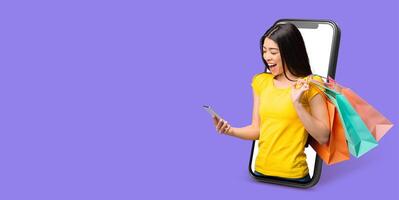 A cheerful customer using a smartphone with a large screen to shop online. She holds colorful shopping bags, immersed in a pleasant online purchasing experience against a solid background. photo