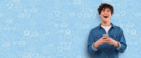 A young man is joyfully using his smartphone to shop online, surrounded by icons representing delivery and e-commerce. The background features a collage of shopping and communication symbols. photo