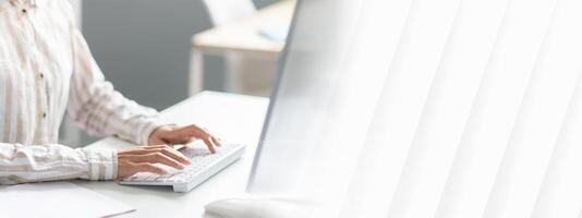 Unrecognizable woman employee working on computer at desk in office, cropped image of lady typing on keyboard, writing email or communicating online photo
