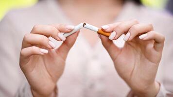Stop smoking concept. Unrecognizable woman breaking cigarette outdoors, closeup image with selective focus photo