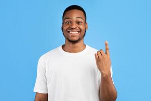 African Man Showing Number One Counting On Fingers Smiling To Camera Standing On Blue Background. Studio Shot photo