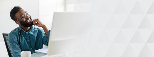 A young male manager, successful and focused, works diligently at his office desk. The modern workspace features a clean design, promoting productivity and creativity, copy space photo