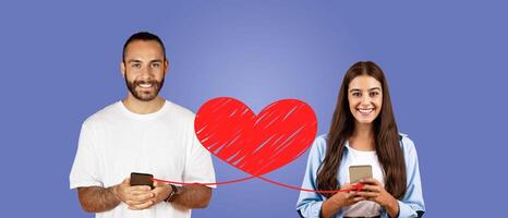 A couple expresses their affection on St. Valentine's Day by using their smartphones to send loving messages. They are smiling and enjoying their connection, isolated against a solid background. photo