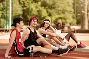 Multinational millennial athletes speaking to each other during their break at outdoor basketball arena, free space. Cheerful young sportsmen relaxing and getting ready for new game outside photo