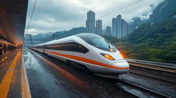 A sleek high speed train pulls into a contemporary station with towering buildings in the background. Lush mountains rise in the distance as rain soaked platforms reflect the vibrant train. photo