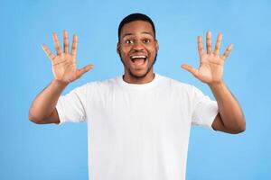 Joyful Black Man Showing Number Ten With Both Hands Smiling To Camera Posing Over Blue Background. Studio Shot photo