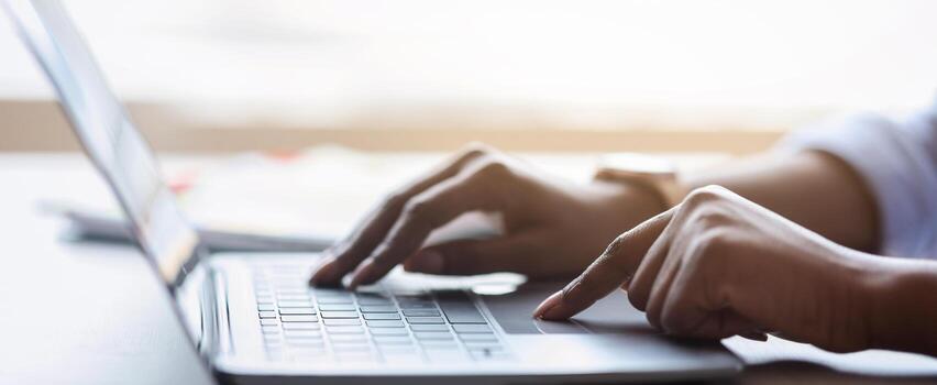 Closeup of unrecognizable black female working on laptop, typing on computer keyboard while working in office, side view, cropped image photo