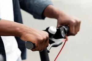 Lifestyle Concept. Closeup of unrecognizable african american boy holding handle of black electric kick scooter photo
