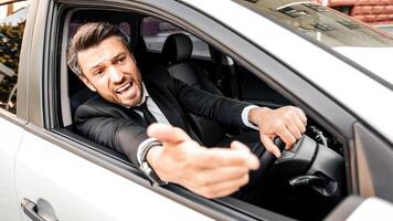 Mad businessman driving luxury car, stuck in traffic, late to airport, copy space. Furious middle-aged man in expensive suit screaming and gesturing to other drivers while driving auto photo