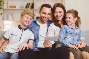 Cheerful Family Using Smartphone Browsing Internet Together Sitting On Couch At Home On Weekend. Mobile App Concept photo