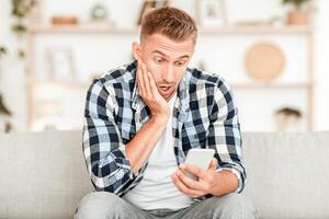 Frontal portrait of man looking agitated at display of his cell phone, impressed by media content from web, free space photo