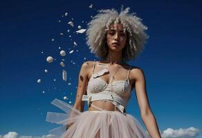 A woman with an afro and a tulle skirt is standing on a beach photo