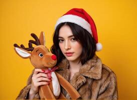 Beautiful young woman in santa hat holding a reindeer plush toy photo