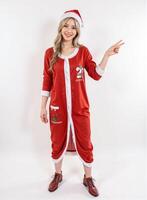 Young lady in full Santa Claus attire pointing at the viewer with a bright and merry Christmas look photo
