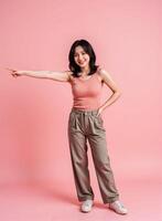 Young asian woman pointing at something on a pink background photo