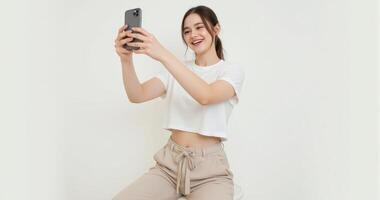 A woman sitting on a stool taking a selfie photo
