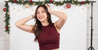 A woman in a maroon top posing in front of a christmas backdrop photo