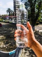 a hand holding a drinking water bottle that only has a small amount of water photo