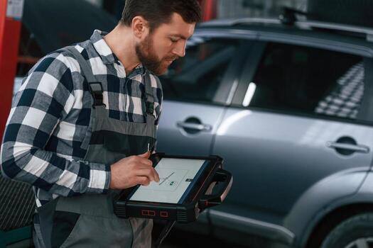 Graphi,c information ,is on the tablet. Man in uniform is working in the auto salon photo