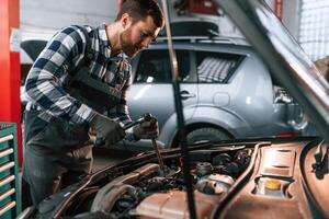 Car details., Repairing the vehicle. Man in uniform is working in the auto salon photo