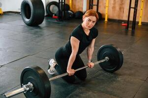 Leaning on the barbell. On the floor.. Beautiful, strong woman is in the gym photo