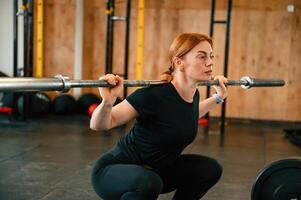 Lifting the barbell. Beautiful strong woman is in the gym photo