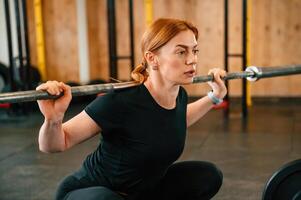 Lifting the barbell. Beautiful strong ,woman i,s in the gym photo