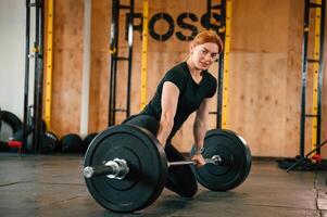 Leaning ,on the ,barbell. On the floor. Beautiful strong woman is in the gym photo