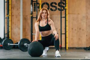 Front, view. Sitting,, barbell on the floor. Beautiful strong woman is in the gym photo