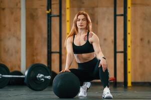 Front, view.. Sitting, barbell on the floor. Beautiful strong woman is in the gym photo