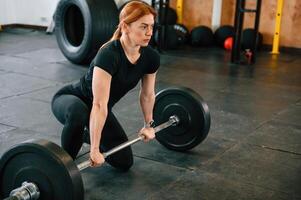 Ready to lift the barbell. Beautiful strong woman is in the gym photo