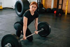 Leaning ,on, the barbell. On the floor. Beautiful strong woman is in the gym photo