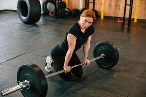 Leaning on the barbell. On the floor. Beautiful ,strong woman is in the gym photo
