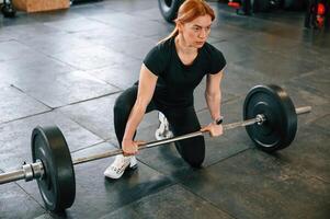 Ready to, lift the barbell.. Beautiful strong woman is in the gym photo