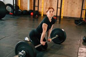 Leaning, on, the barbell. On the floor. Beautiful strong woman is in the gym photo