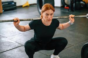 Lifting the barbell. Beautiful strong woman is, in the gym photo