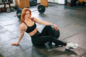 Sitting on the, floor. Beautiful strong woman is in the gym photo